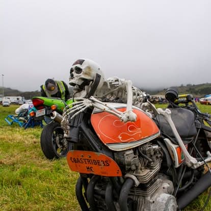 Vintage motorcycle with a custom fuel tank and helmet at Pacific Coast Dream Machines event in Half Moon Bay, California.