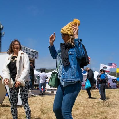 Vintage music enthusiast in stylish clothing and eyewear enjoying live tunes at Pacific Coast Dream Machines event.