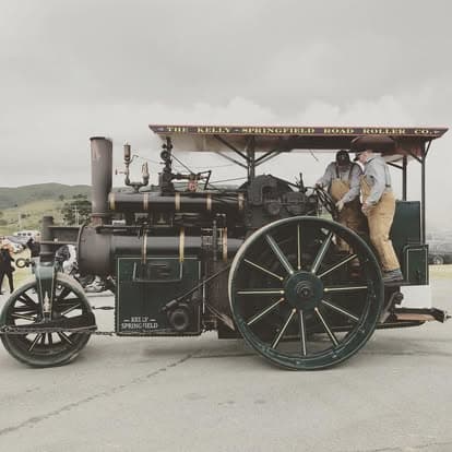 Vintage tractor with a steam engine and large wheel on display at Pacific Coast Dream Machines festival in Half Moon Bay.