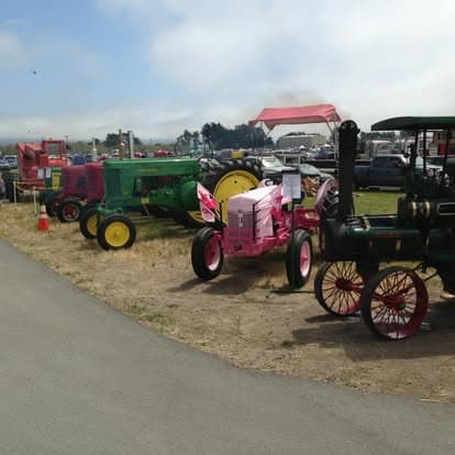 Vintage tractor with large agricultural tires on display at Pacific Coast Dream Machines event in Half Moon Bay, California.