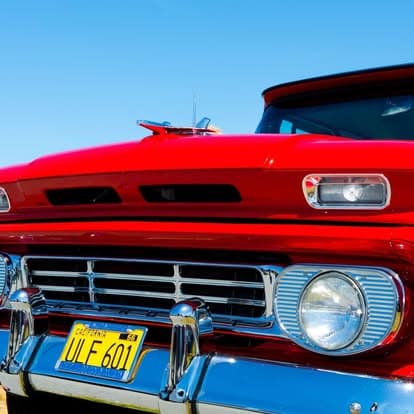 Vintage red classic truck with a chrome grille and hood ornament at Pacific Coast Dream Machines event in Half Moon Bay.